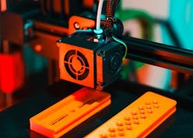 Detailed view of a 3D printer in action, extruding orange plastic components.