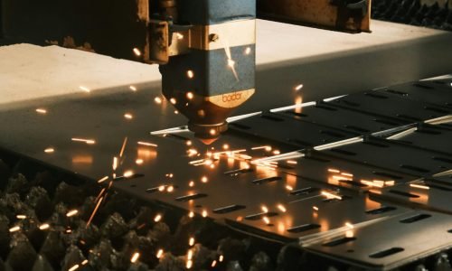 Close-up of a laser cutter in action, producing sparks in a modern manufacturing facility.